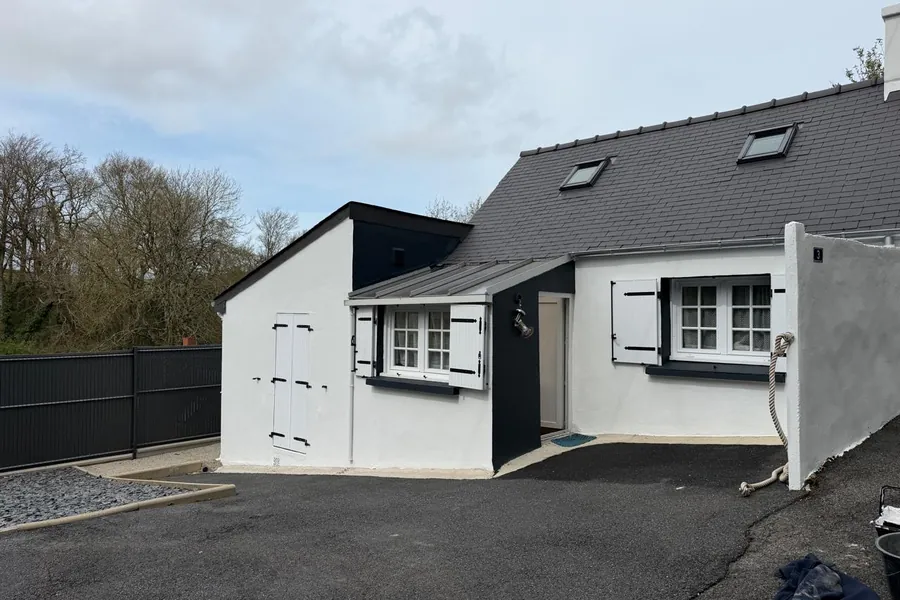 Maison rénovée par JMI Rénovation : façade et extension peintes en blanc, volets gris anthracite
